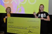 Lu Ann Reeb, Director of Entrepreneurial Studies and Business Studies, and a student hold an oversized check in the amount of $5,000. The student is smiling and also holding a small, clear trophy.