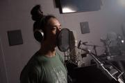 Student in a sound room wearing headphones and speaking into a microphone