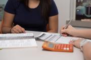 two people looking at forms with calculator