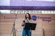 A woman standing at the UnCommon Stage, holding a microphone and smartphone device.