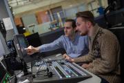 Two people sitting at a control board