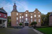 Photo from meticulous courtyard of a sandy brick castle with tower, on the sides are two smaller buildings 