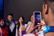 A group of students being photographed on a phone at graduation