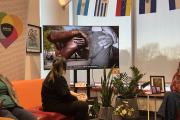 People sitting on the couch in the Intercultural Student Affairs office watching a video about the Embrace Monument