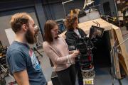 Three people standing around a camera