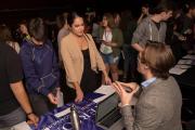 Two people speaking to someone at a booth at a job fair