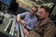 A faculty member with a student at a TV control panel