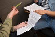 Two people holding paper and pencils