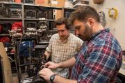 Two students working together with audio/visual equipment in a storage space
