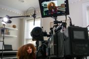 A student being filmed, seen through a camera's secondary miniature monitor