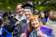 A graduate in regalia posing with their family
