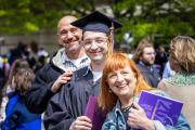 Student in cap and gown posing with parents