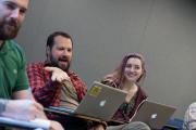 Students having a lively discussion during class with laptops on their desks