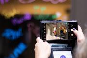 A pair of hands holding up a smartphone to take a photo at a campus event