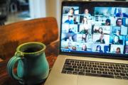 A zoom call on an open laptop with a mug beside it