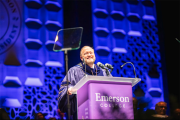 President Bernhardt smiles at a purple podium in front a purple background