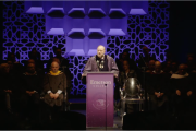 Emerson College President Jay Bernhardt standing at a lectern, delivering his inauguration remarks
