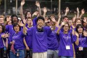 A diverse group of students excitedly pose for the picture, arms raised