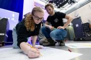 Two students preparing for the EVVY Awards, an awards show celebrating Emerson spirit and service across organizations and initiatives; one is sketching on a piece of paper, laying out the awards stage