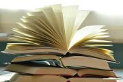 On a stack of books, the pages of a wide open book flare out