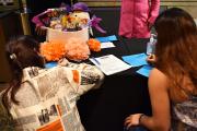 Students fill out surveys on a table with the Career Fair raffle prize and a flyer for one of LiveNation's intern positions