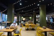 A well lit dining area with cafe string lights above tables and seating for students