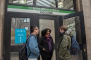 Three students conversing and smiling in front of the Boylston Green Line subway station entrance