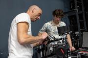 A professor assisting a student with a professional camera during class