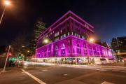 The International College of Management Sydney at night, brightly lit with purple lights