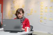 Student working at a laptop in front of a board covered in post-its