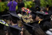 Seated graduates with decorated caps one says Thanks Mom