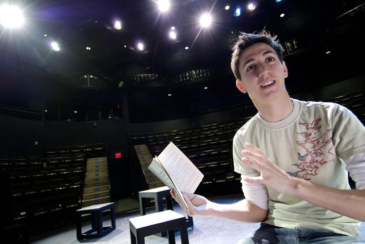 A student rehearses a play on stage