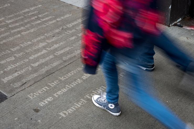 A student walks by poetry written on the sidewalk