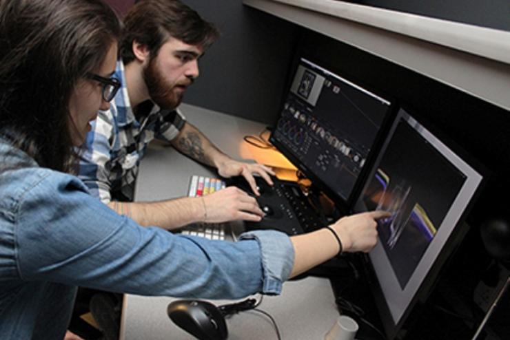 Students working together at computer in digital post-production suite