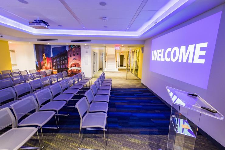 Empty chairs in screening room in the Visitor Center with Welcome sign and purple lighting