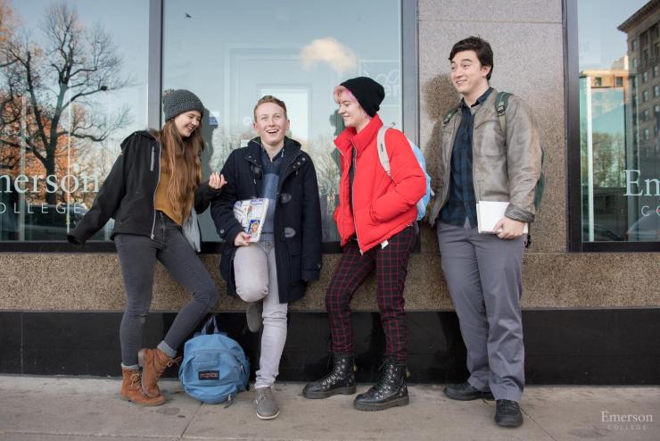 Group of friends standing against glass wall with Emerson College written on it