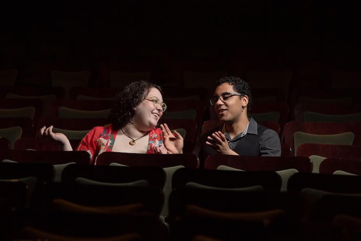 Two Emerson students speaking to one another inside a theater