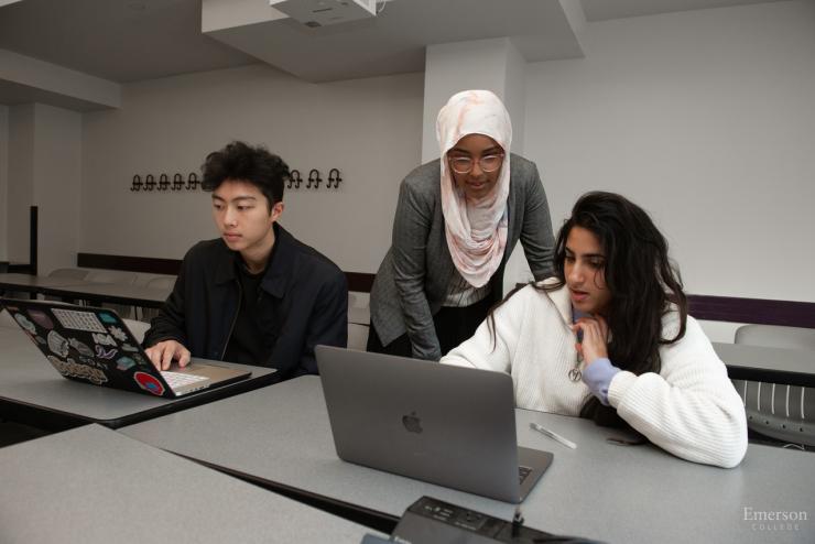 Faculty member helping students on computer
