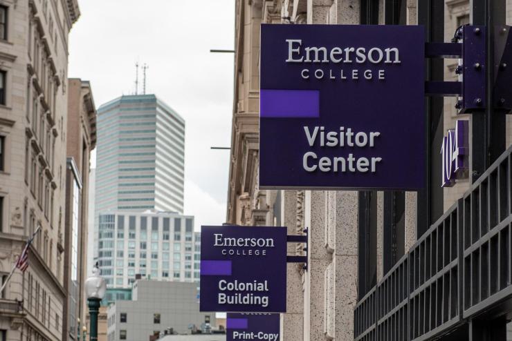 View of Emerson College's Visitor Center and Colonial Building signs hanging from buildings.