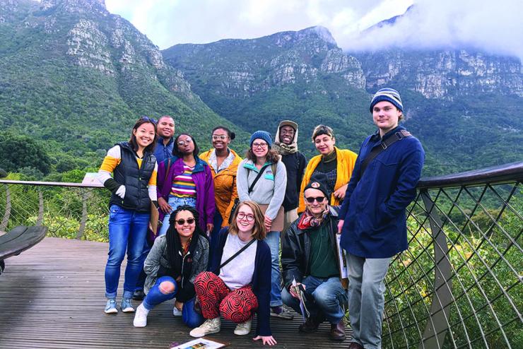 Students in China with professor standing on a bridge, with mountains behind them