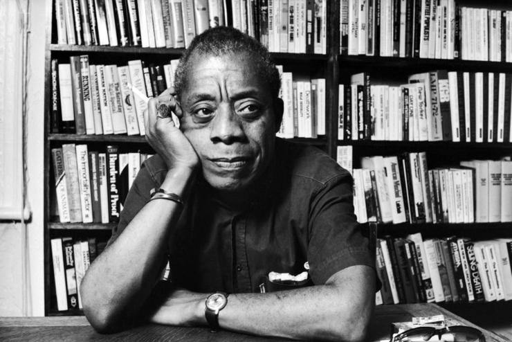Black and white photo of James Baldwin sitting at desk (New Yorker Magazine, 2014)