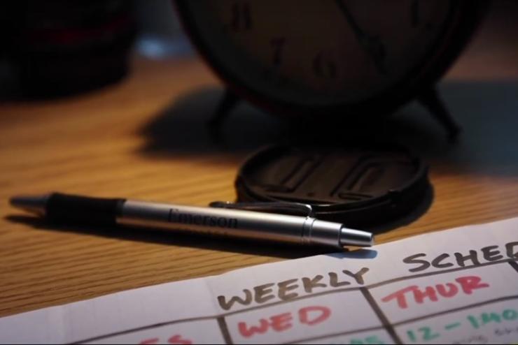 Close-up of a pen and weekly schedule sitting on a desk