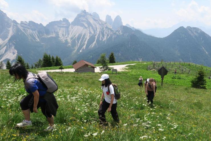 Students walking up a grassy hill with mountains in the background