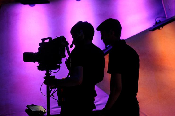 Silhouette of two students working at a camera