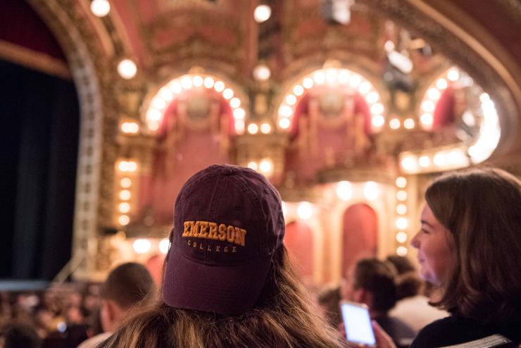 A student wearing an Emerson baseball cap looks at stage in the Cutler Majestic Theatre
