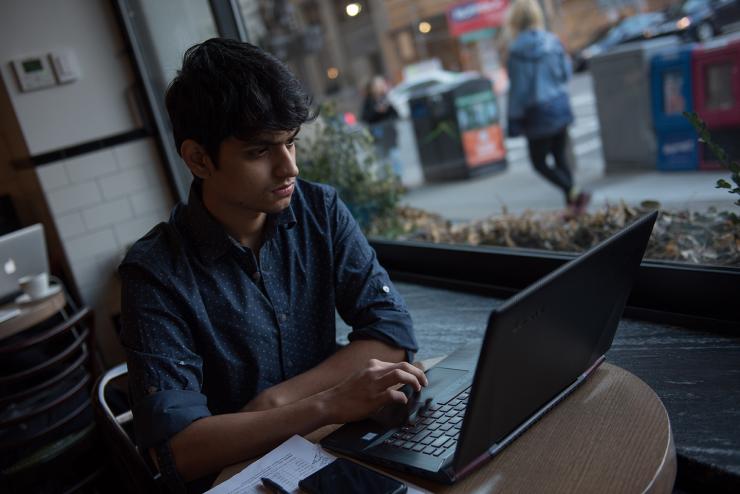 A marketing student working on a laptop in a cafe
