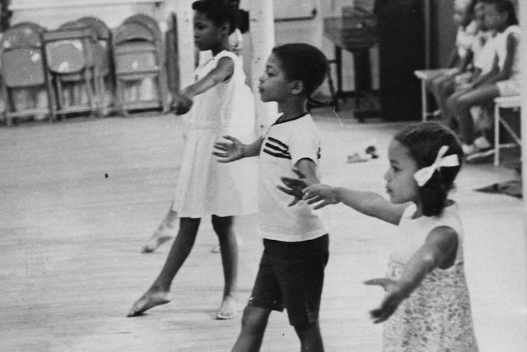 Aged black and white photo of three kids taking a ballet class