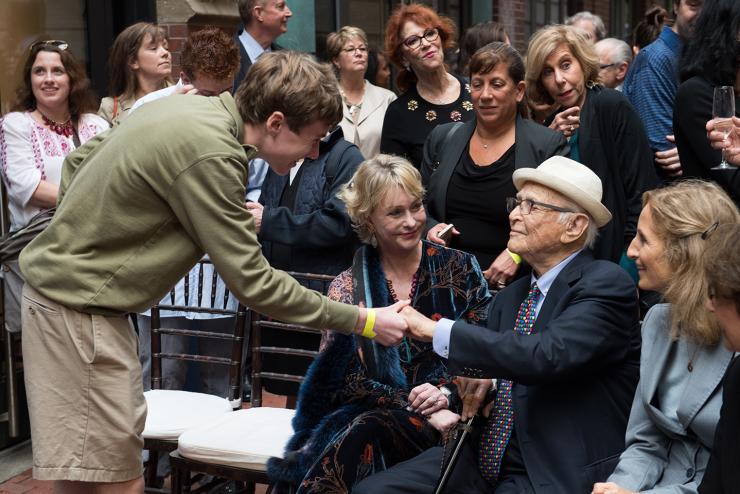 Student reaches down to shake Norman Lear’s hand in a crowd of alumni on Norman Lear Day