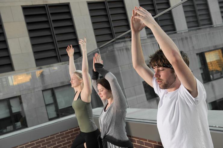 Students doing yoga on the roof of a residence hall