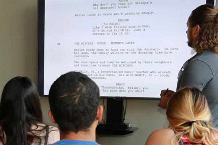 Students looking at a script passage projected onto a display in a screenwriting course